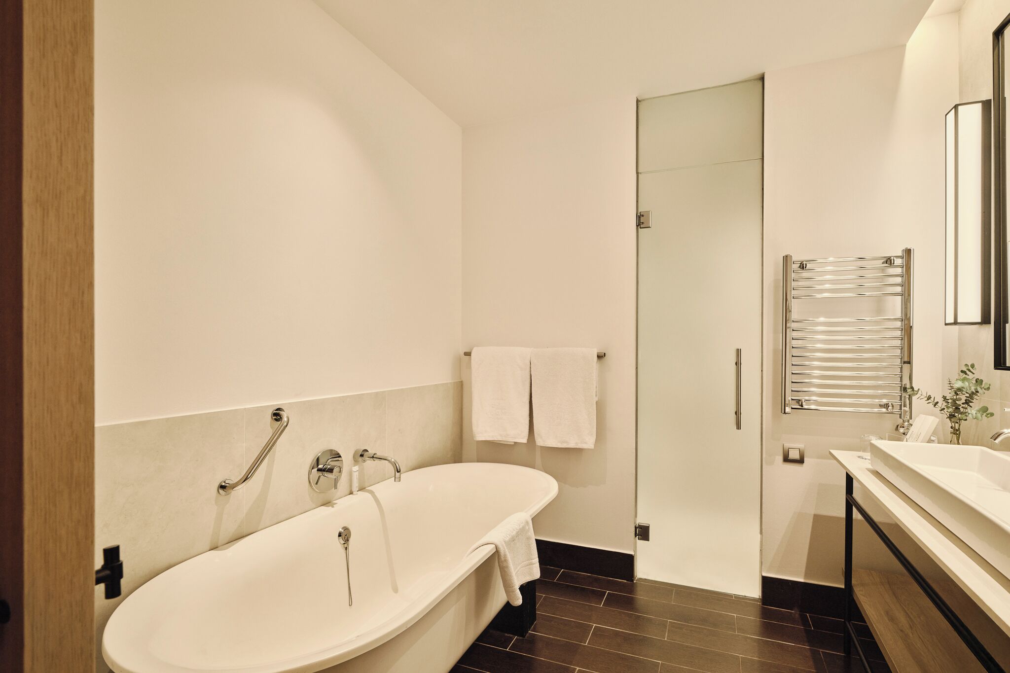 A modern bathroom with a freestanding bathtub, a glass shower enclosure, and a vanity with a mirror.