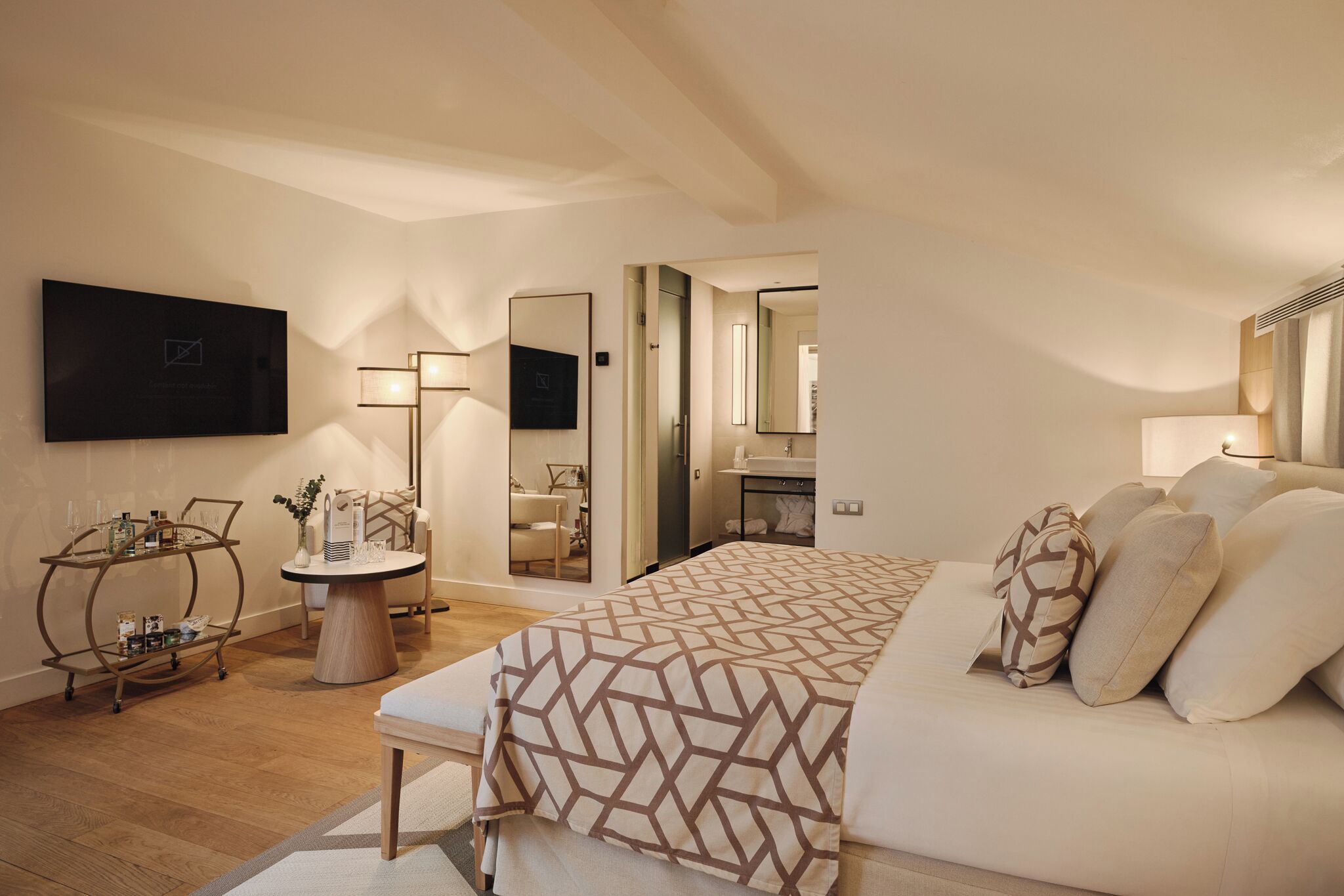 A modern bedroom with a large bed, bedside tables, a mirror, and a TV mounted on the wall.