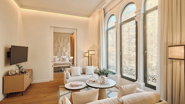 Un salon spacieux comprenant un ensemble de canapés, une table basse et un téléviseur fixé au mur.