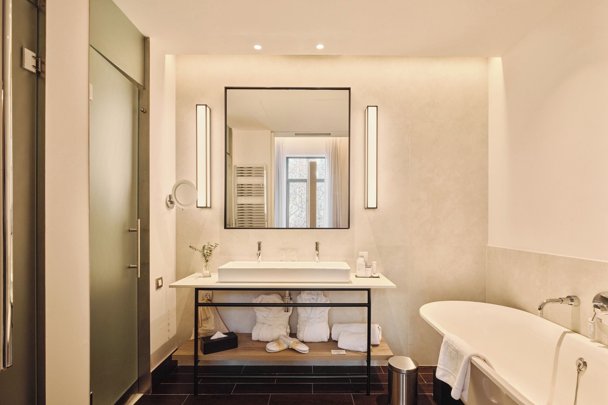 A modern bathroom with a large mirror, a white sink, and a freestanding bathtub.