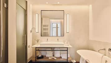A modern bathroom with a large mirror, a white sink, and a freestanding bathtub.