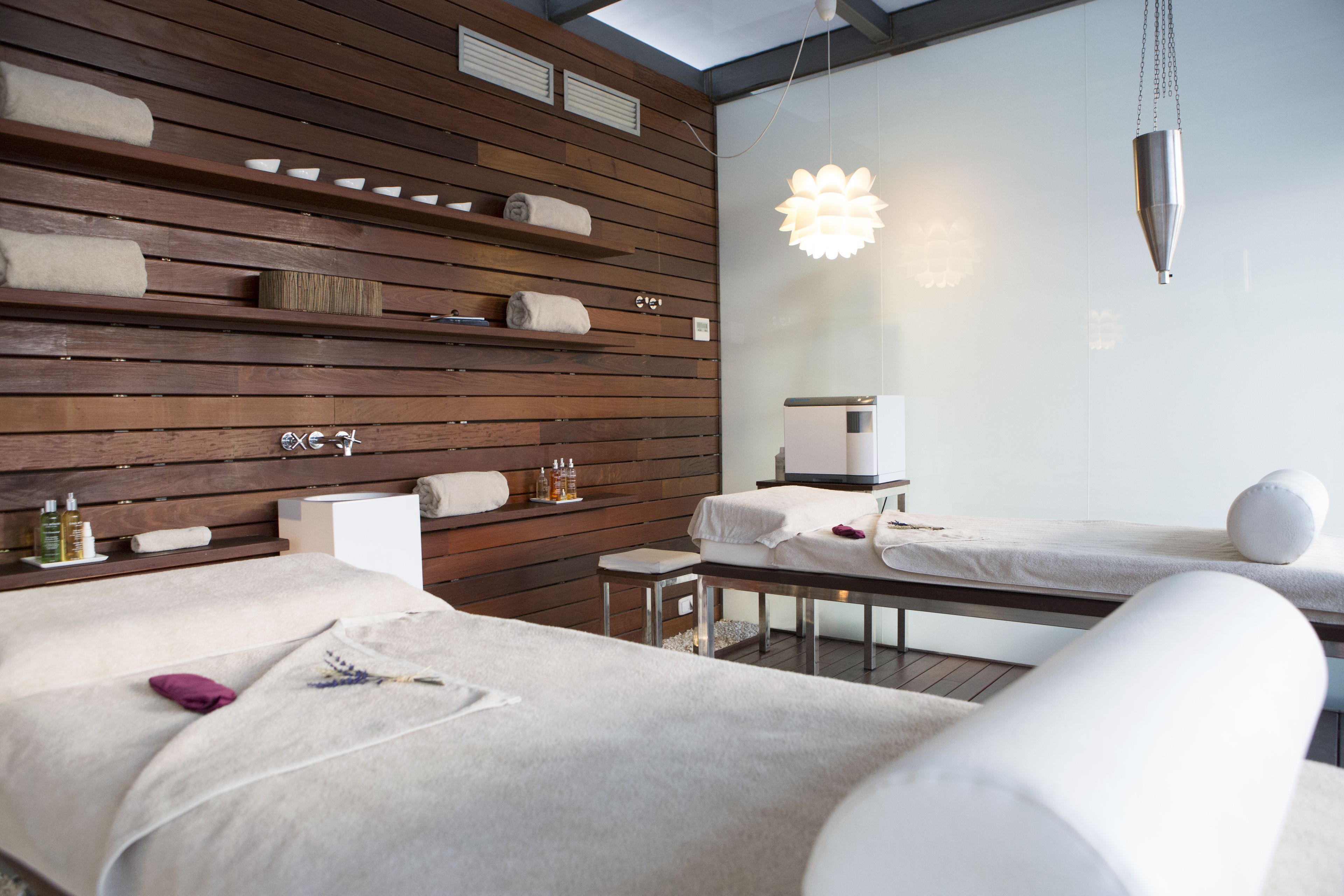 A modern hotel room with wooden panel walls, a large mirror, and two beds with white linens.