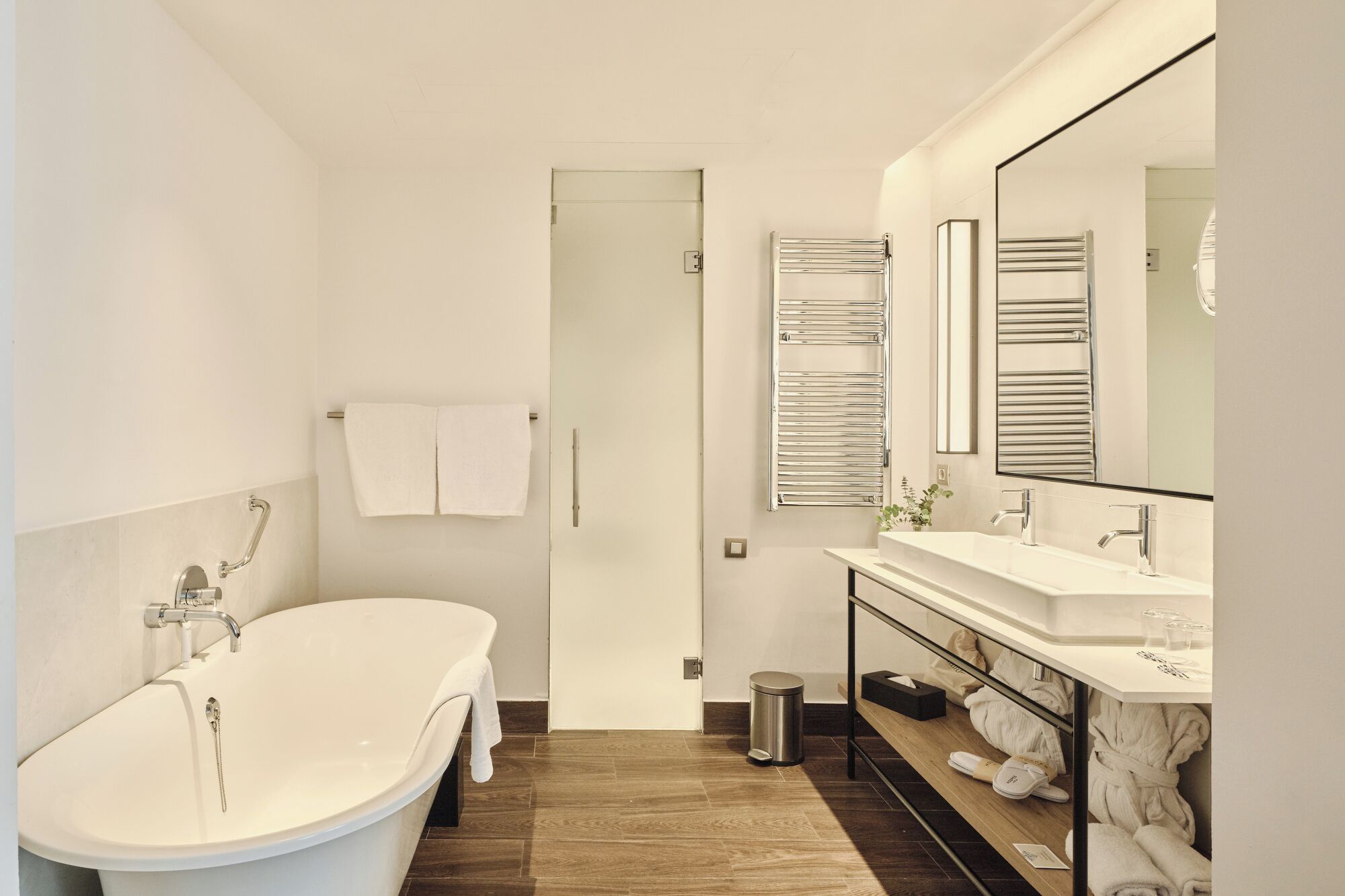 A modern bathroom with a freestanding bathtub, a vanity with a mirror, and a towel rack.