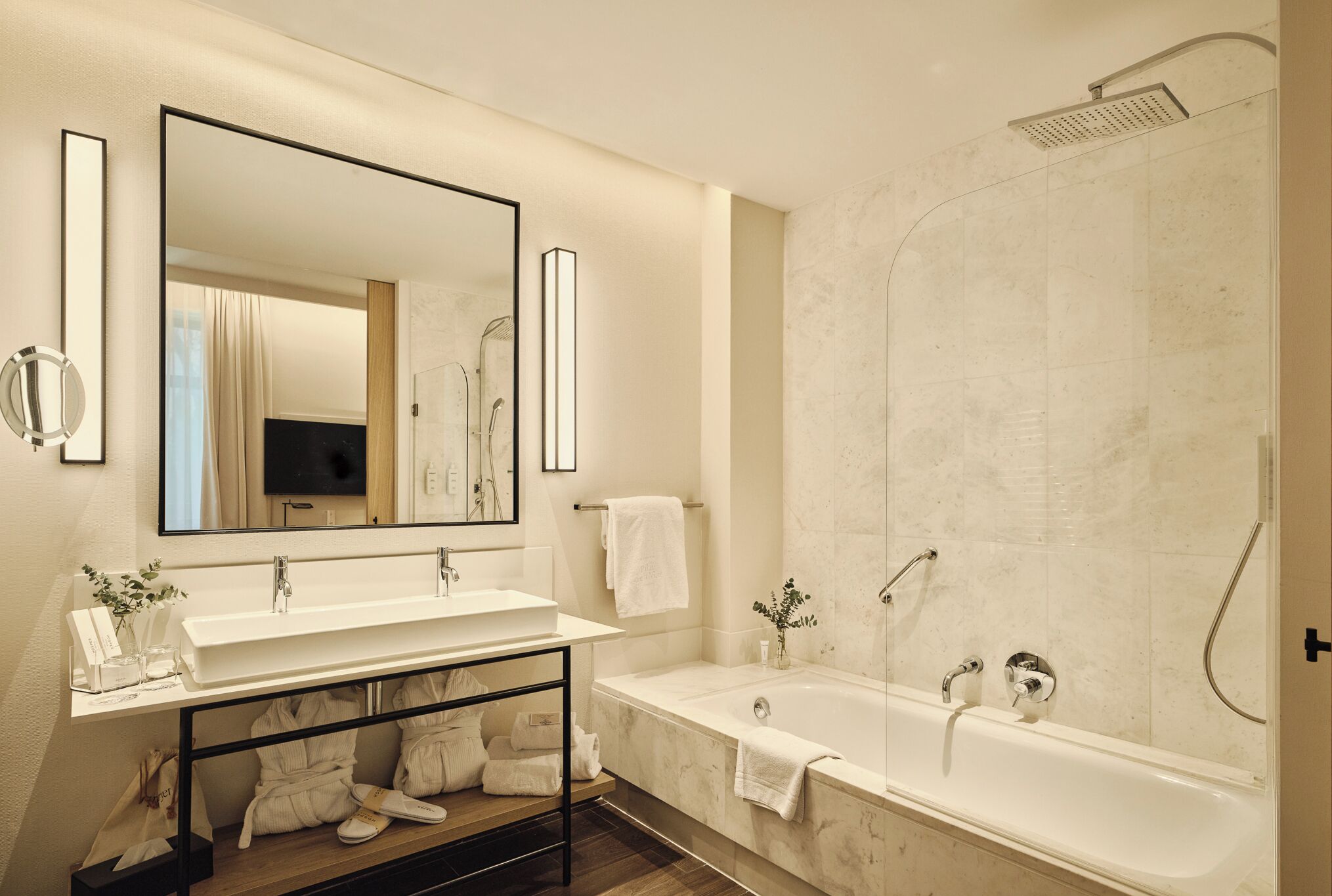 A modern bathroom with a double sink vanity, a large mirror, a bathtub, and a shower.