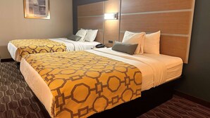 Une chambre d’hôtel avec deux lits, chacun recouvert d’une couvre-lit à motifs, dotée d’une tête de lit avec éclairage intégré et ornée d’un tableau encadré au mur.