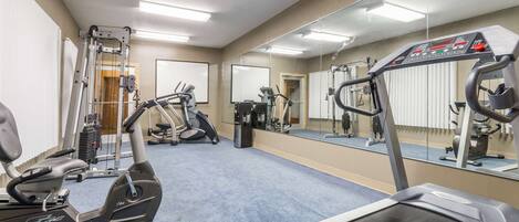 Uma academia com aparelhos de cardio, equipamentos de musculação e espelhos nas paredes.