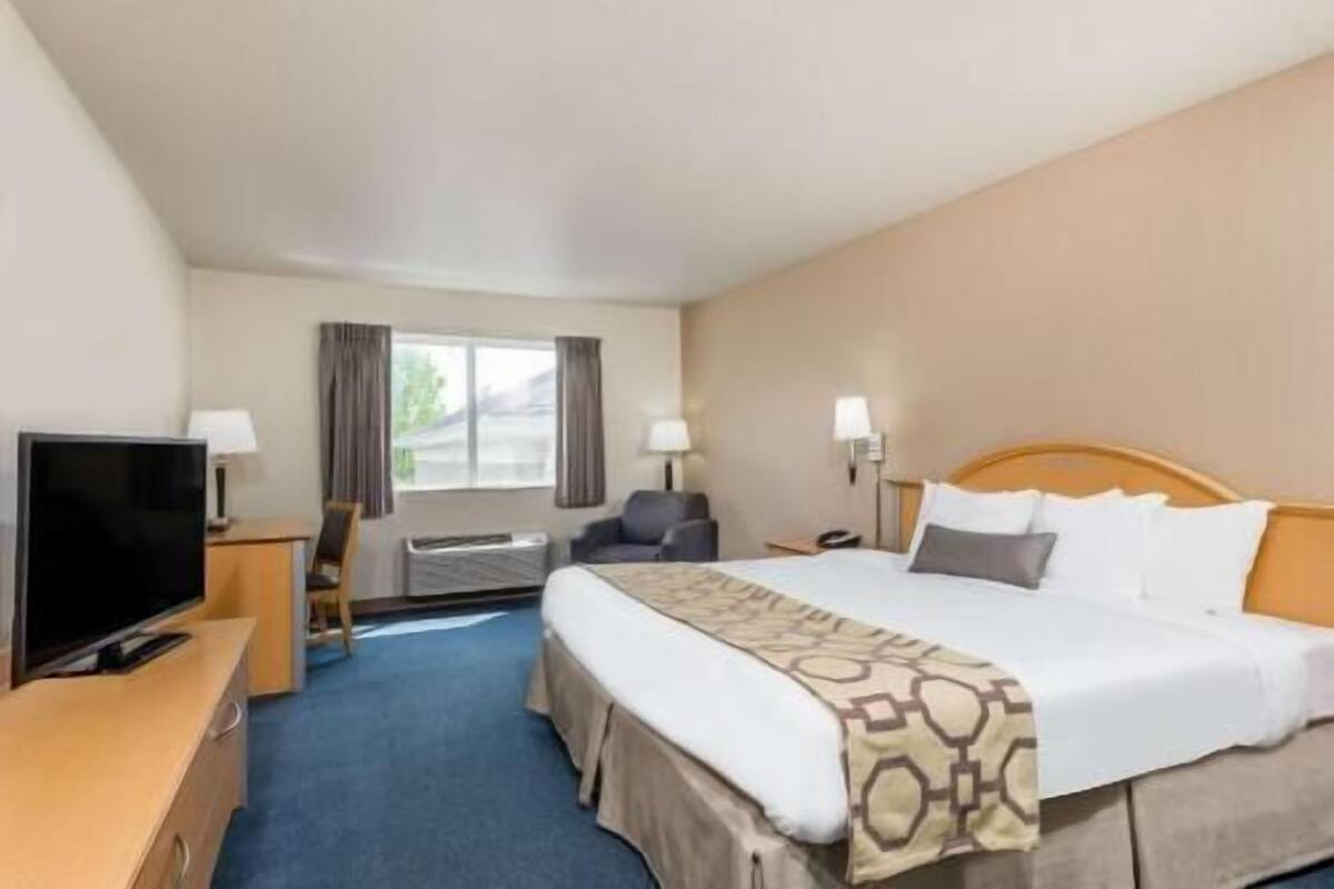 Ein Hotelzimmer mit Bett, Fernseher, Schreibtisch und Stuhl.