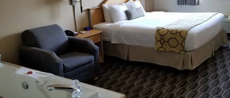 A hotel room with a bed, a chair, a desk, a lamp, a picture on the wall, and a window with curtains.