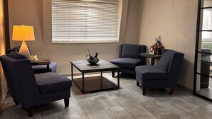 Un salon moderne avec un canapé, des fauteuils, une table basse et une lampe.