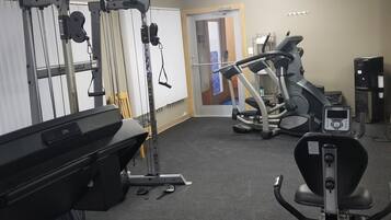 A gym with exercise equipment, a treadmill, and a water dispenser.