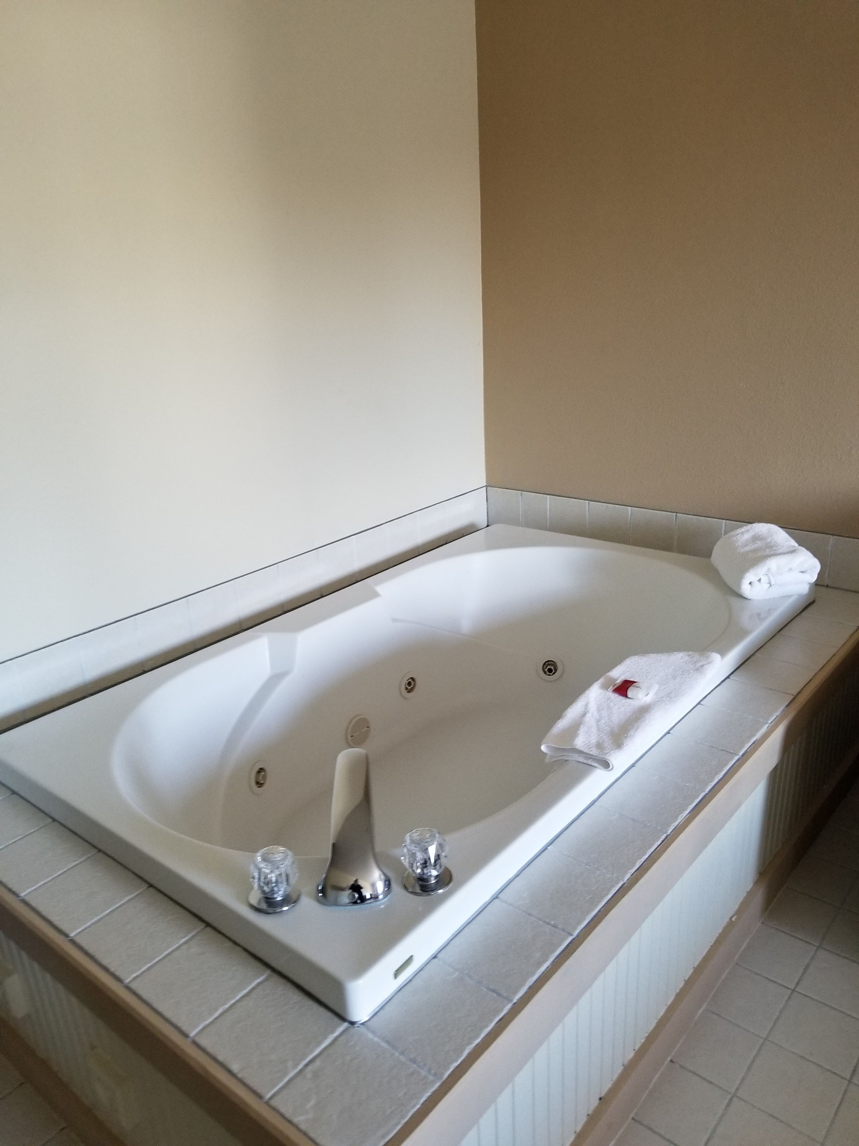 A modern bathroom with a large white bathtub, a shower, and a toilet.