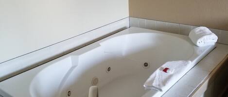 A modern bathroom with a large white bathtub, a shower, and a toilet.