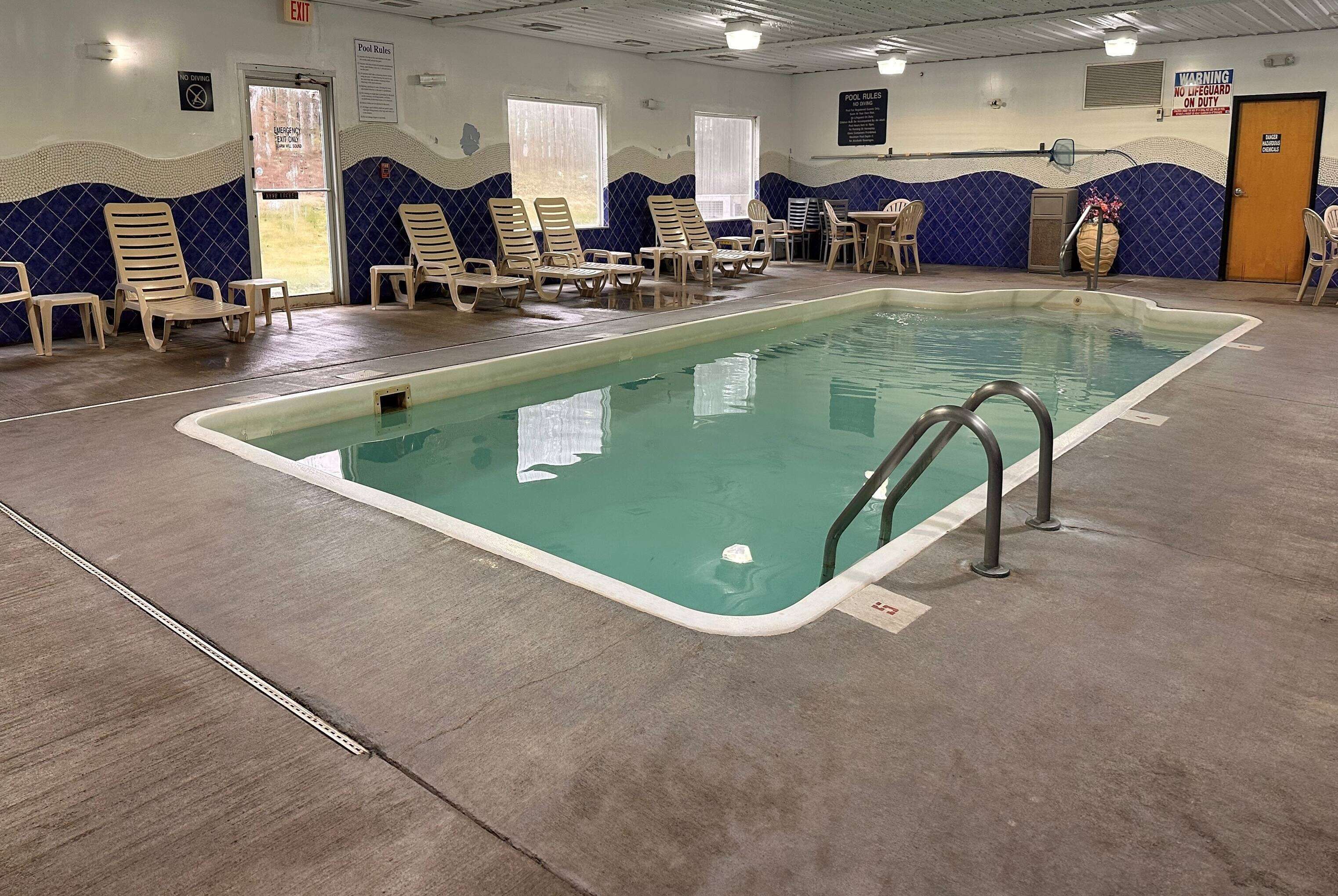 An indoor swimming pool with lounge chairs and a lifeguard chair.