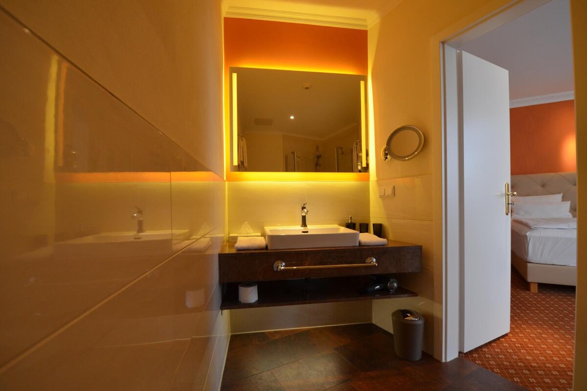 A hotel bathroom with a large mirror, a sink, and a toilet.