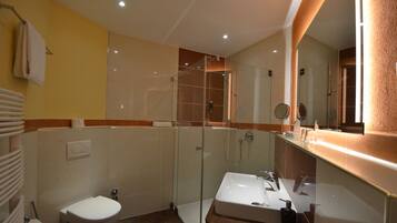 A modern bathroom with a glass-enclosed shower, a white sink, and a toilet.