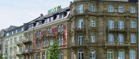 A multi-story hotel with a classic architectural style, featuring balconies and a prominent tower.
