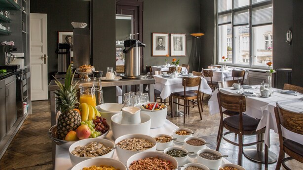 A breakfast buffet with various food items and a dining area with tables and chairs. - Hotel Art Nouveau (Berlin)