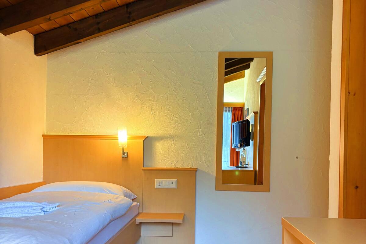 A bedroom with a wooden bed, a nightstand, a mirror, and a wooden dresser.