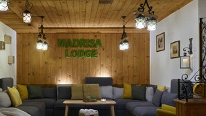 A cozy living room with a large sectional sofa, a small table, and a wall-mounted sign that reads "MADRISA LODGE". - Madrisa Lodge (Klosters-Serneus)