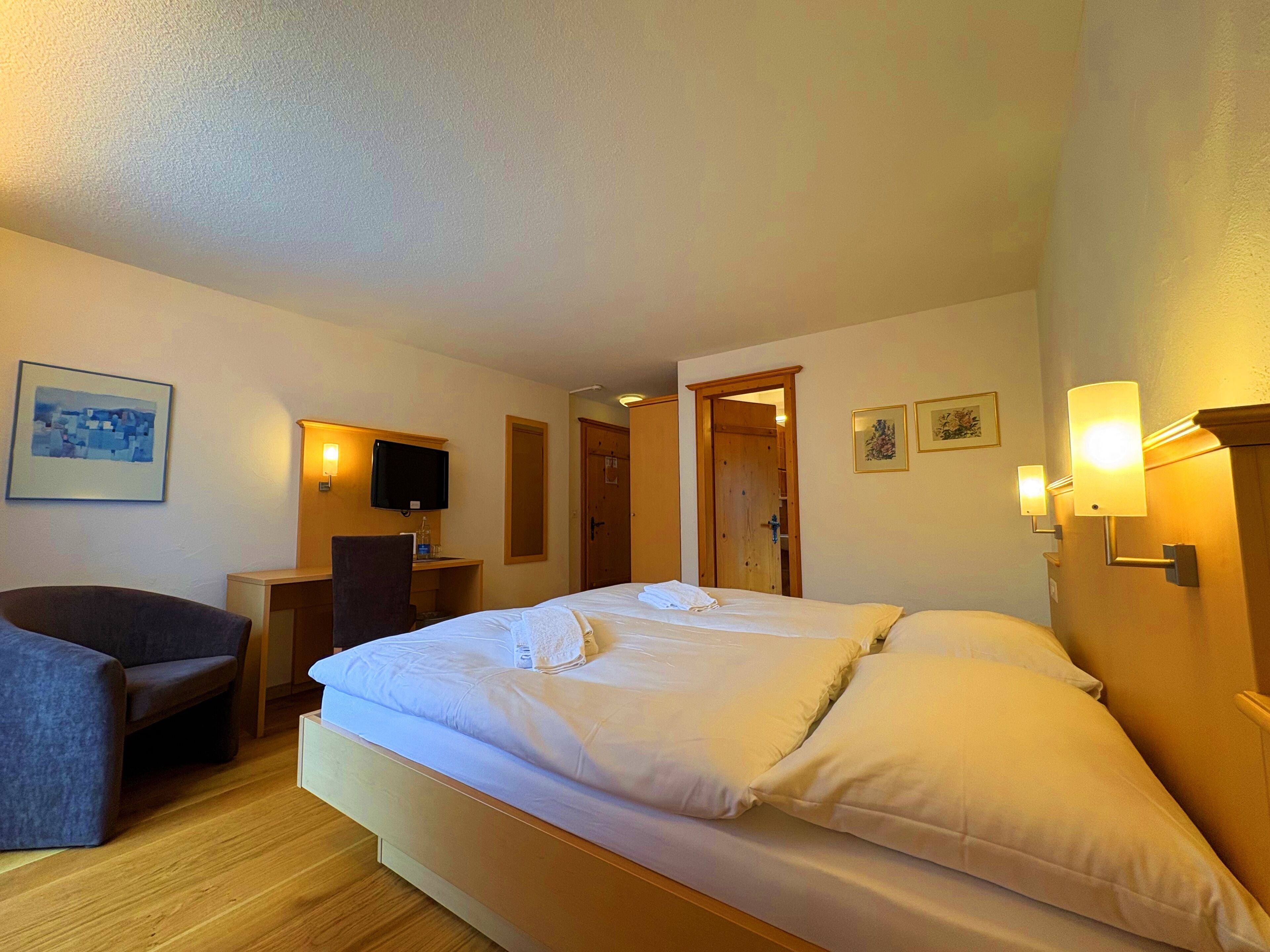 Una habitación de hotel con cama, escritorio, silla y televisor.