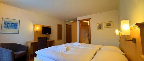Una habitación de hotel con cama, escritorio, silla y televisor.