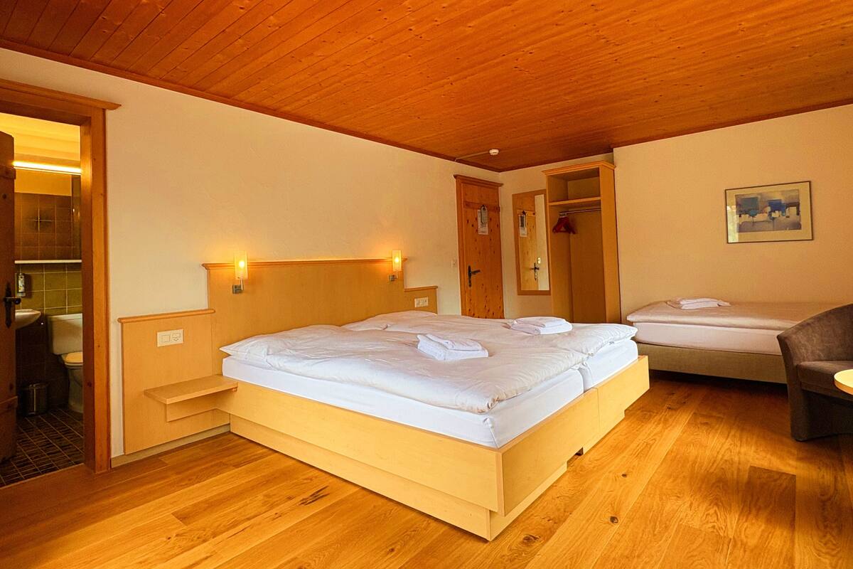 A wooden ceiling and a bed with a headboard in a room.