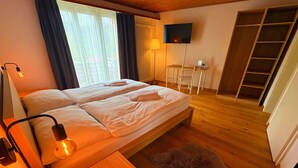 A room with a bed, a TV, a small table, and a fur rug. - Madrisa Lodge (Klosters-Serneus)