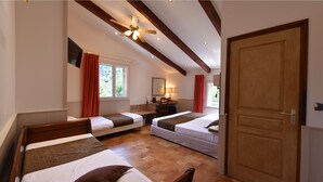 Habitació d'hotel amb dos llits individuals, sostre de fusta, una porta de fusta gran i una finestra amb cortines vermelles.