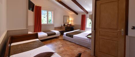 Habitación de hotel con dos camas individuales, techo y puerta de madera, y una ventana con cortinas rojas.