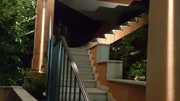 A staircase with a metal railing, leading to a landing with a light fixture.