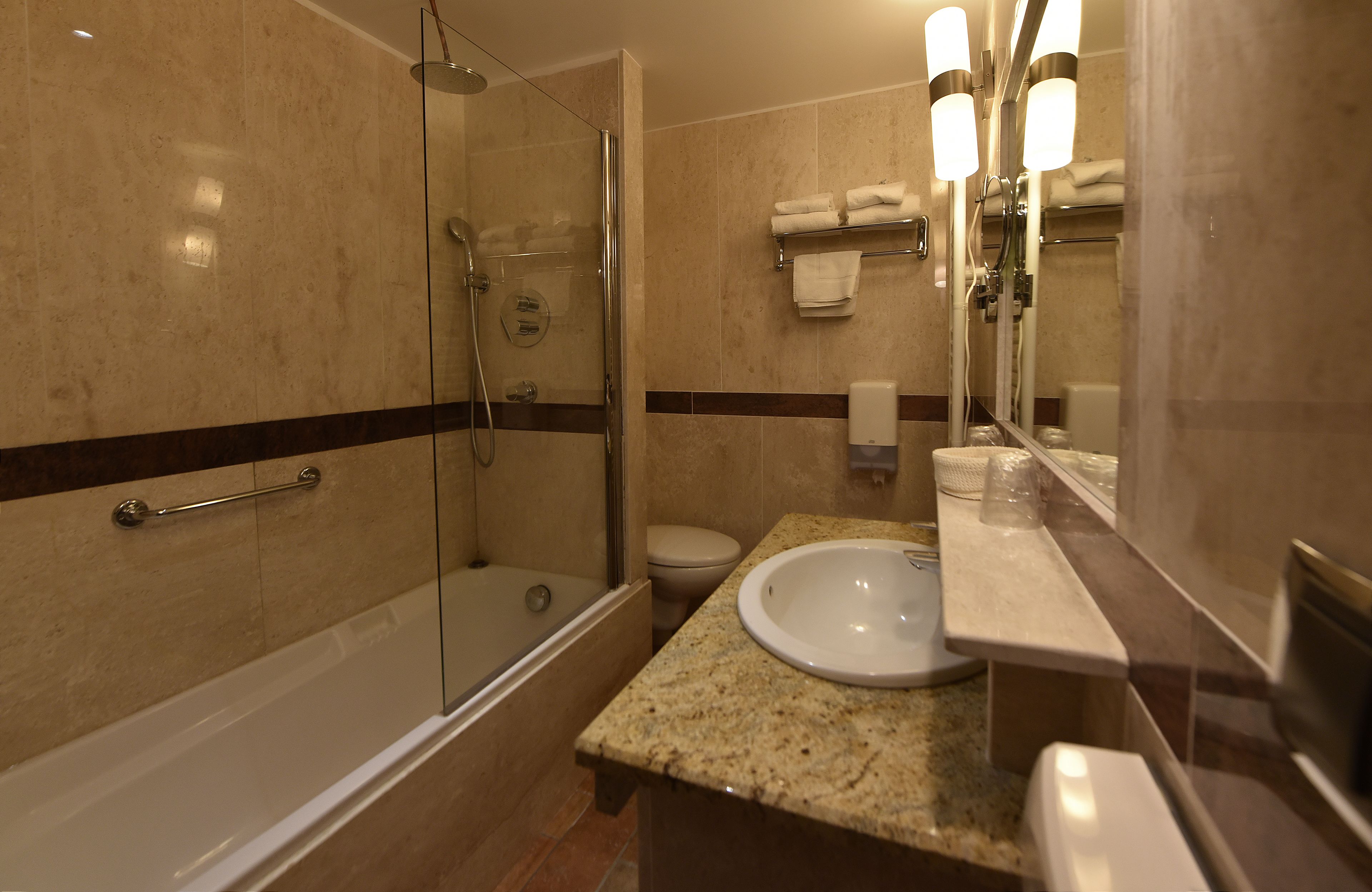 A modern bathroom with a glass-enclosed shower, a white sink, and a toilet.