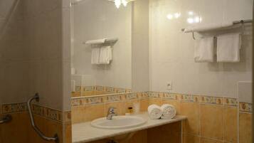 A bathroom with a sink, mirror, and handrails.