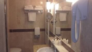 Un bany d'hotel amb vàter, rentapeus, mirall, assecagordes i assecador de mans.