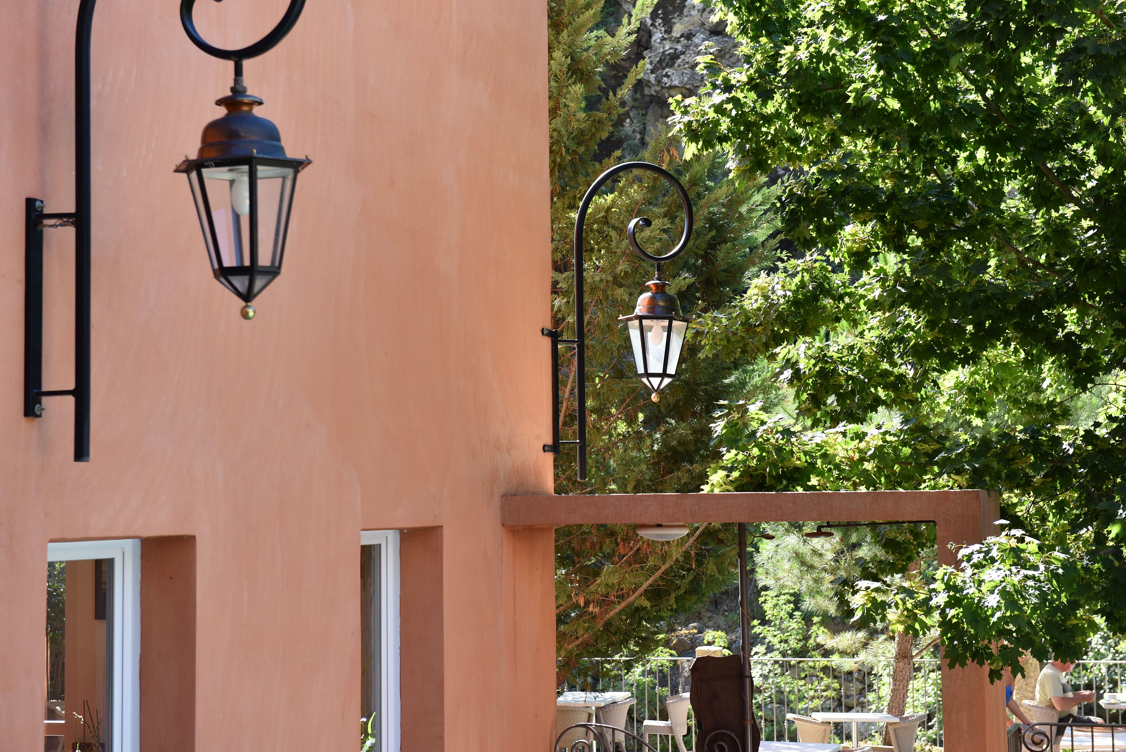 A building with outdoor seating and two hanging lanterns.