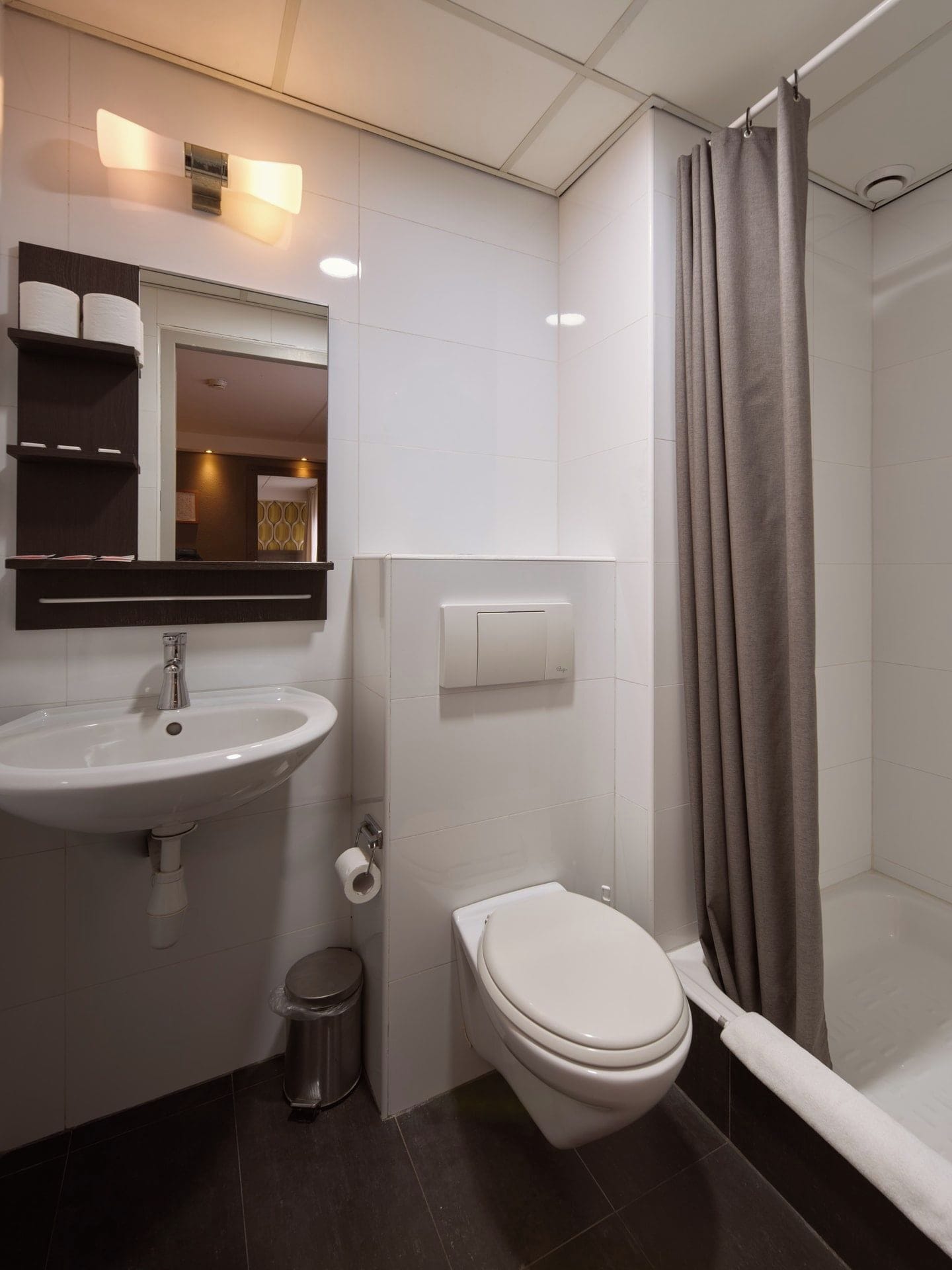 Une salle de bain moderne avec un lavabo, des toilettes et une douche, le tout de couleur blanche.