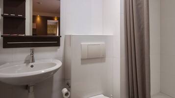 Une salle de bain moderne avec un lavabo, des toilettes et une douche, le tout de couleur blanche.