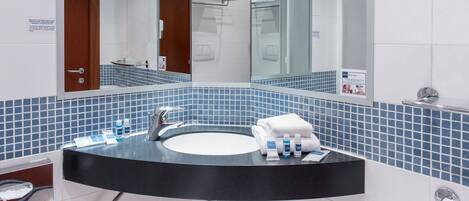 A modern bathroom with a black sink, blue-tiled walls, and a large mirror.