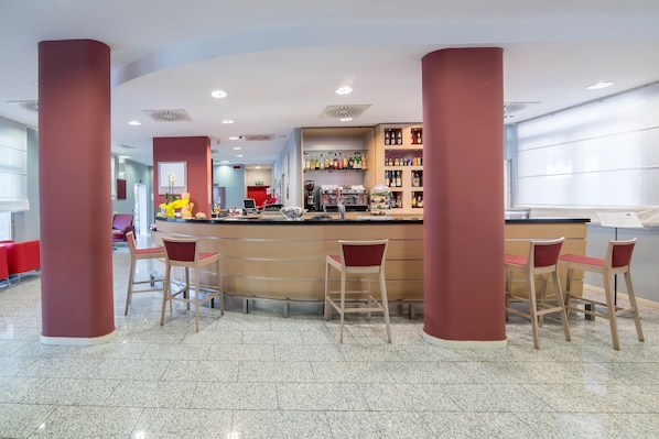 A modern bar area with a counter, bar stools, and a beverage display. - Idea Hotel Torino Mirafiori (Turin)