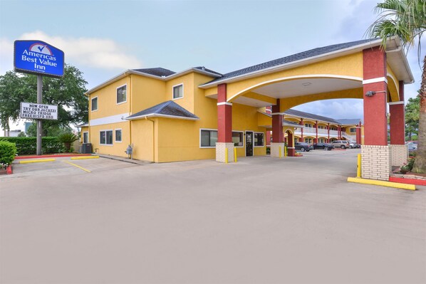 A yellow building with a blue sign for America's Best Value Inn. - Americas Best Value Inn Baytown (Baytown)