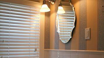 Un baño con un lavamanos blanco, dos luces empotradas en la pared y un espejo grande.