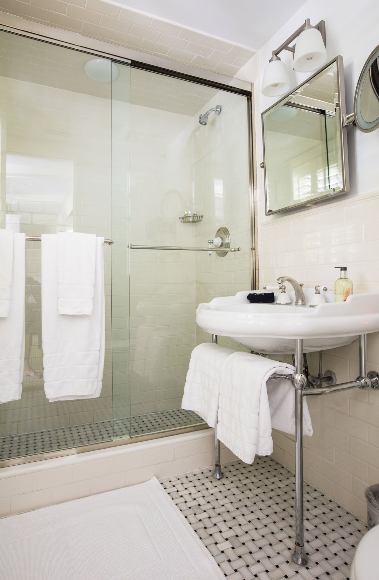 A bathroom with a glass-enclosed shower, a white sink with chrome fixtures, and a mirror above the sink.