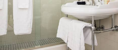 A bathroom with a glass-enclosed shower, a white sink with chrome fixtures, and a mirror above the sink.