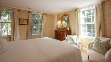 A bedroom with a large bed, a dresser, a chair, and a mirror.