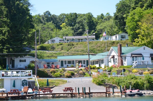 A waterfront hotel with a dock, outdoor seating, and a small boat. - Lake View Motel (Cooperstown)