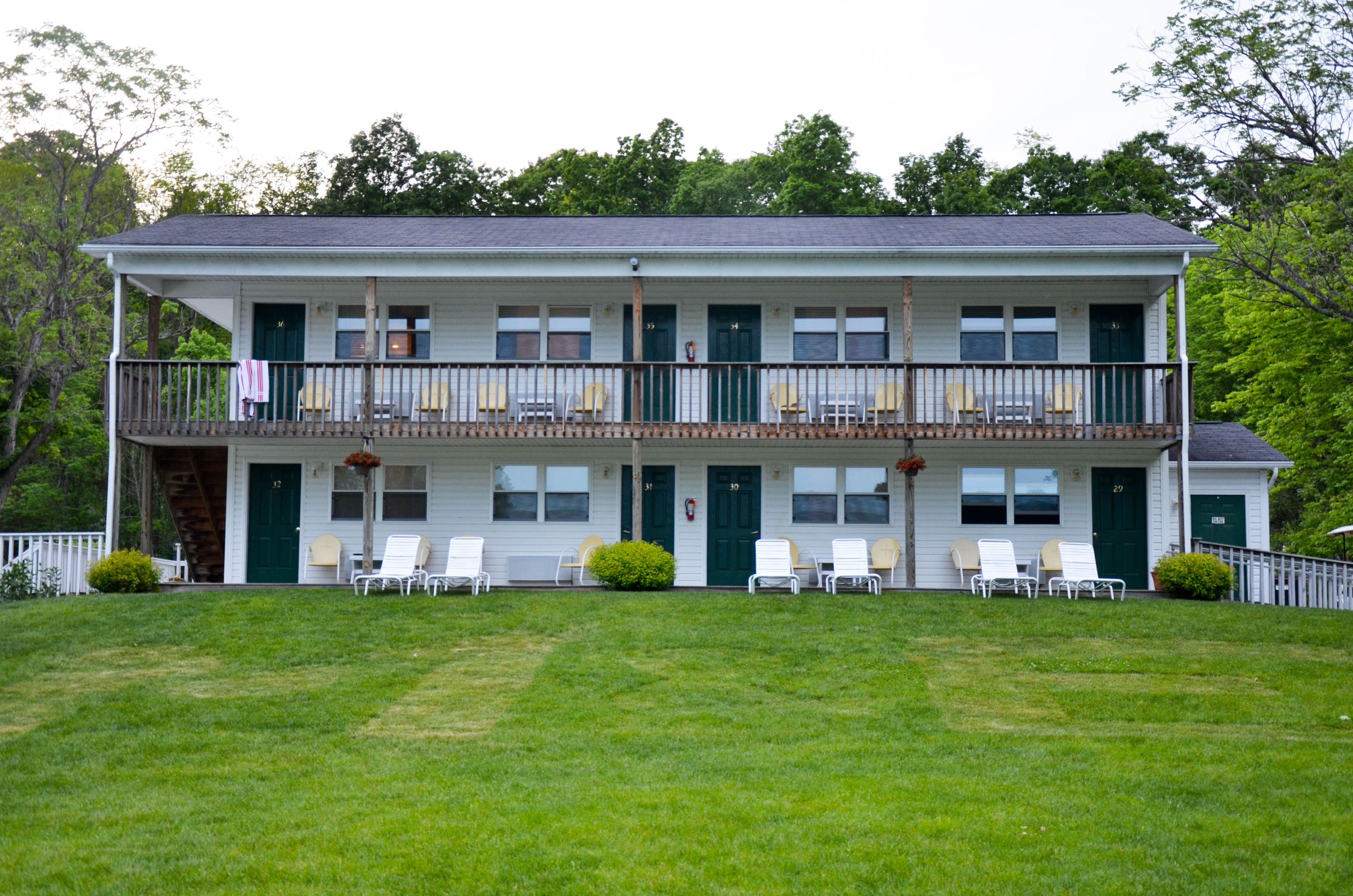A two-story building with a balcony, multiple doors, and outdoor seating.