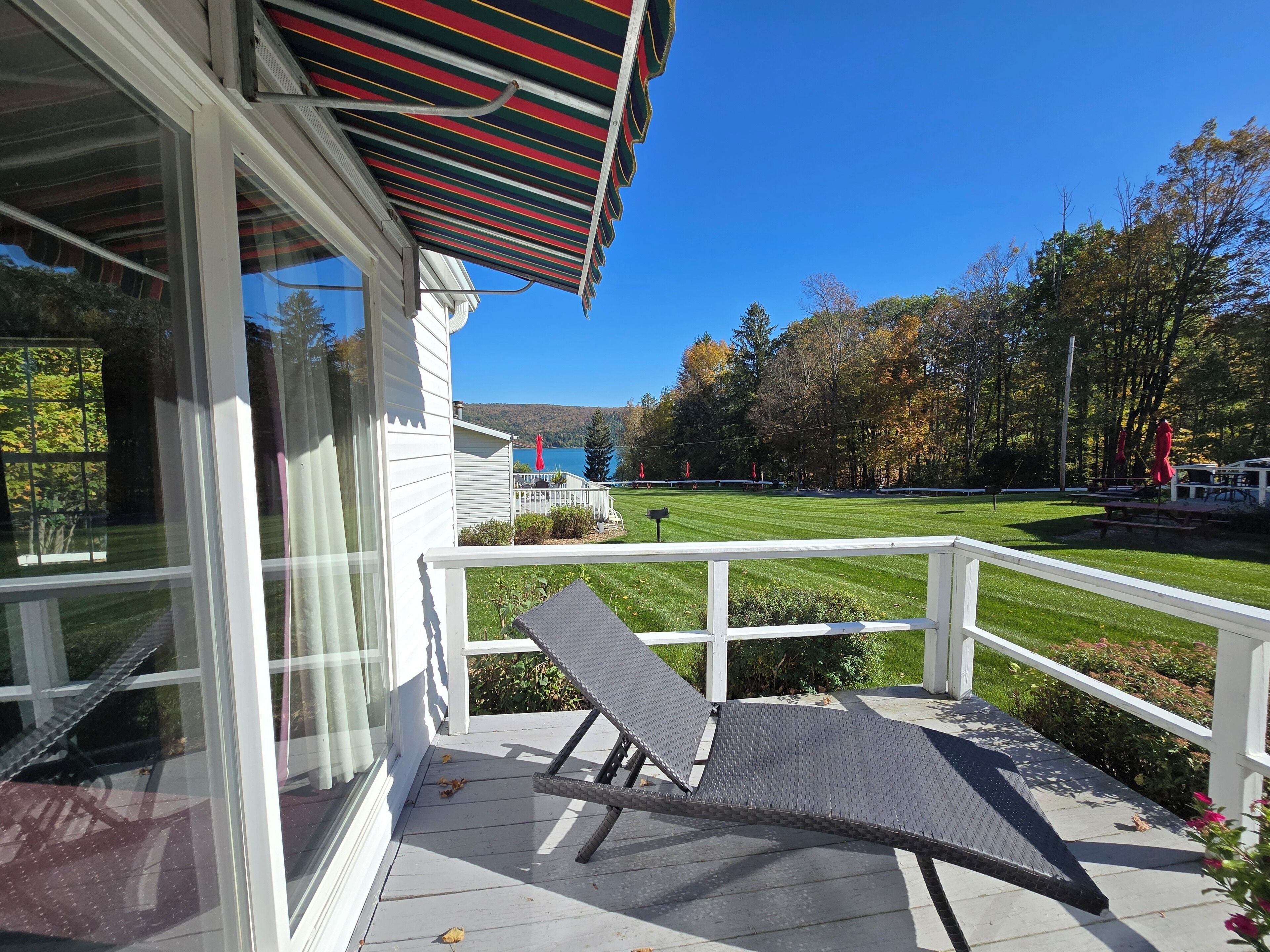 A covered porch with a view of a well-maintained lawn and trees.