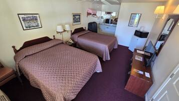 A hotel room with two beds, a desk with a computer, a microwave, and a ceiling fan.