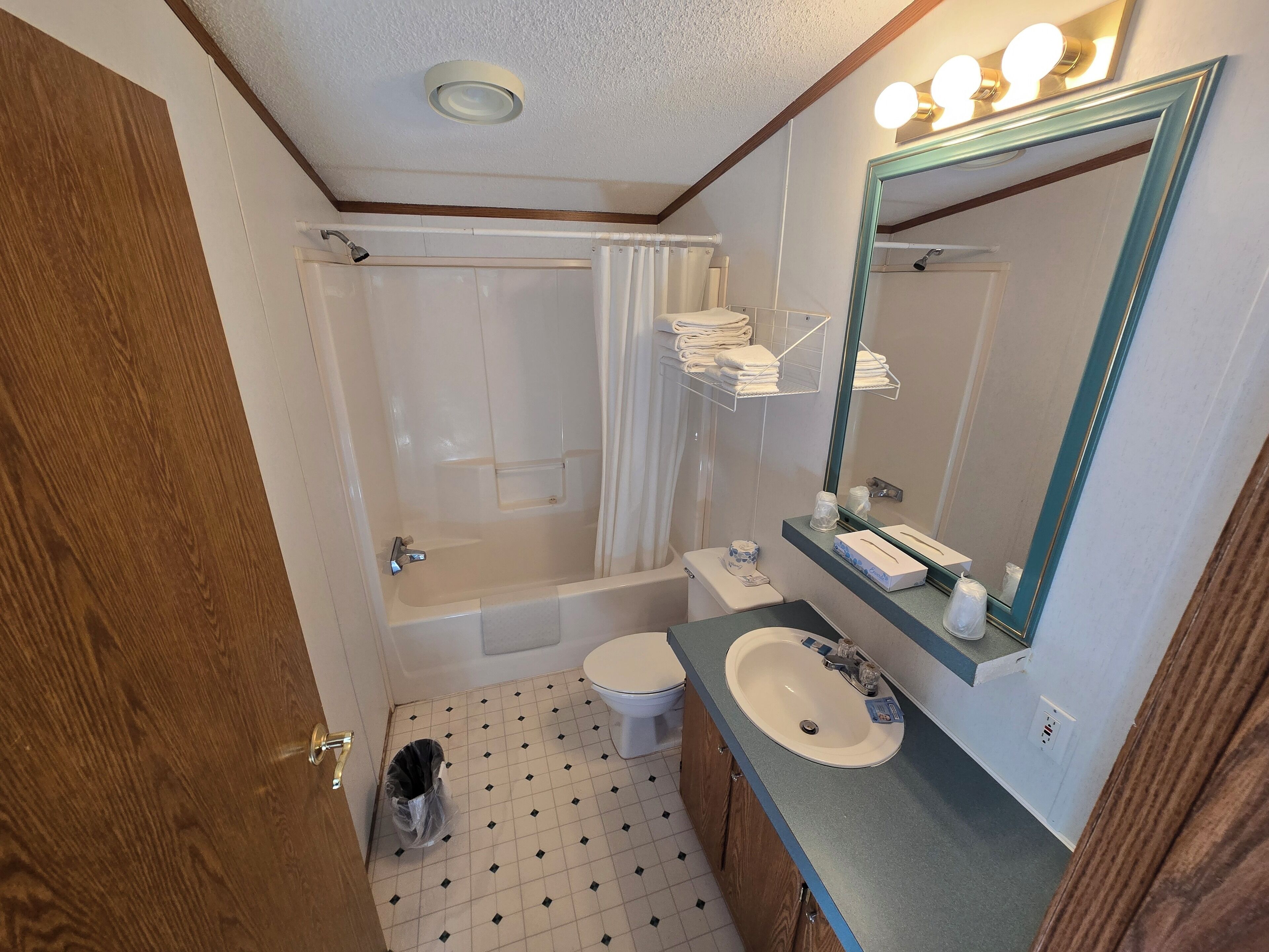 A bathroom with a bathtub, toilet, sink, and a mirror with lights.