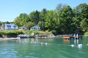 A waterfront property with a dock, lounge chairs, and a small boat. - Lake View Motel (Cooperstown)