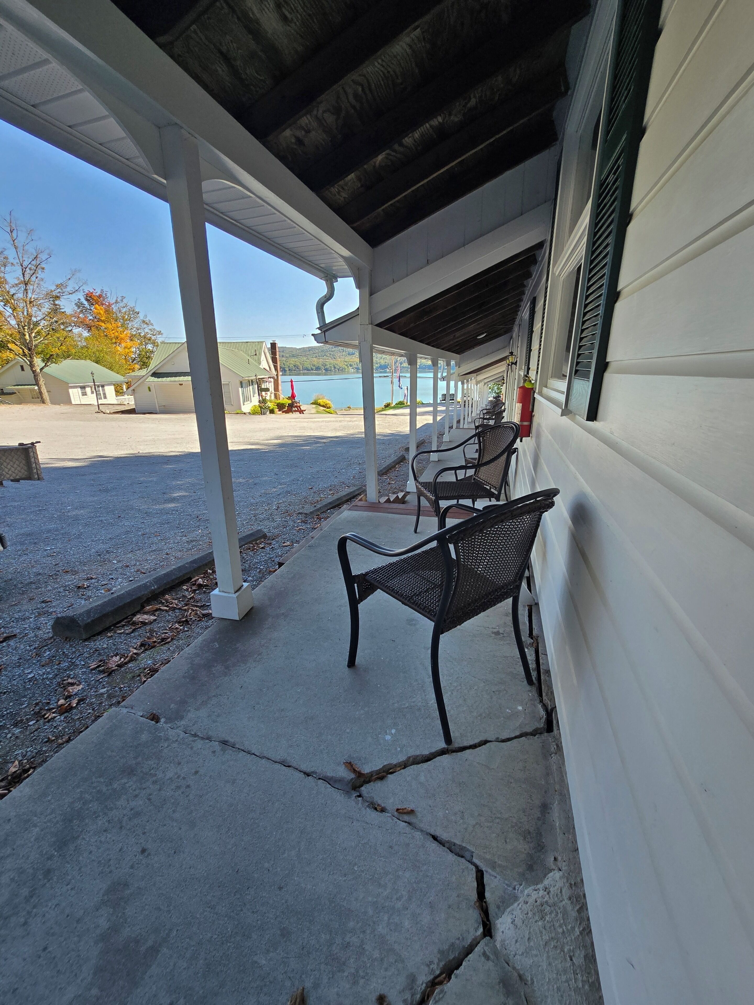 A covered outdoor seating area with benches, a gravel path, and a view of a lake.